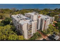 An aerial view of a condo complex surrounded by trees and a waterfront backdrop at 2699 Seville Blvd # 805, Clearwater, FL 33764