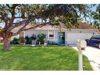 Charming single-story home with a beautiful lawn, mature tree, and a welcoming turquoise front door at 3238 6Th W Ave, Palmetto, FL 34221