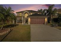 Two-story home with an attached two car garage, mature palm trees, and a well-manicured lawn at 5410 Treig Ln, Wesley Chapel, FL 33545