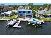Waterfront home featuring a private dock, two boat lifts, and beautiful blue siding with a matching metal roof at 5449 Manatee Point Dr, New Port Richey, FL 34652