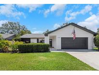 Charming single-story home featuring a well-maintained lawn, grey garage door, and black trim, perfect for suburban living at 14007 Middleton Way, Tampa, FL 33624