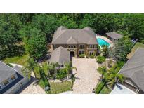 Aerial view of a large home with pool, lush landscaping, brick paver driveway and tile roof at 14809 Ninebark Ct, Land O Lakes, FL 34638