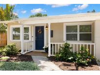 Charming home featuring a vibrant blue door and covered front porch, with lush landscaping at 4519 S Grady Ave, Tampa, FL 33611