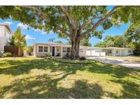 Charming single-story home featuring a beautifully landscaped front yard, a large shade tree, and a covered carport at 4519 S Grady Ave, Tampa, FL 33611