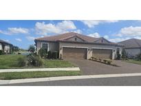 Charming home with two-car garage, landscaped lawn, and brick driveway on a sunny day at 5406 Rushmere Ct, Palmetto, FL 34221