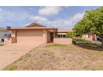 Tan single Gathering home showcasing an attached garage, covered entry, and a well-maintained yard at 9205 Ledgestone Ln, Port Richey, FL 34668