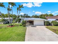Charming single-story home with a well-maintained lawn, mature palm trees, and a spacious driveway leading to an attached garage at 10828 99Th Pl, Seminole, FL 33772
