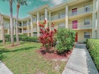 Well-maintained condo building featuring multiple balconies, mature landscaping, and vibrant red door accents at 2690 Coral Landings Blvd # 122, Palm Harbor, FL 34684