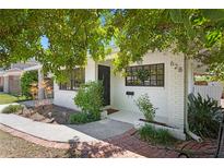 Charming white brick home featuring dark trim windows, a welcoming front porch, and verdant landscaping at 628 Bosphorous Ave, Tampa, FL 33606