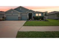 Charming single-story home featuring a well-manicured lawn, two-car garage, and stone accents on the facade at 7323 Steer Blade Dr, Zephyrhills, FL 33541