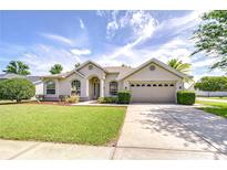 Inviting single-story home with a well-manicured lawn, arched windows, and a two-car garage at 7824 Primula Ln, New Port Richey, FL 34654
