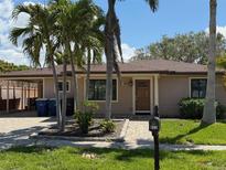Charming single-story home with a manicured lawn, mature palms, and an inviting walkway to the front door at 833 Lantana Ave, Clearwater Beach, FL 33767