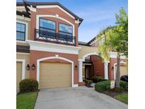 Beautiful two-story townhome with tan stucco, a garage, and a small black wrought iron balcony at 11548 Crowned Sparrow Ln, Tampa, FL 33626