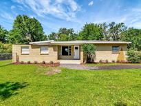 Inviting single-story brick home with a well-kept lawn, pretty landscaping, and a bright white front door at 2054 Deerwood Rd, Seffner, FL 33584