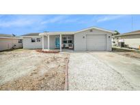 Charming single-story home features a white gravel driveway, light grey exterior and a cozy front porch at 3422 Trask Dr, Holiday, FL 34691