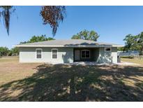 Back of home features a covered lanai with two windows and a door, plus mature landscaping at 4416 Tevalo Dr, Valrico, FL 33596