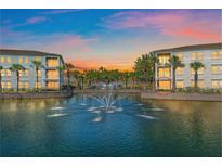 Water view of a condo with three stories, balconies, water fountain, palm trees, and sunset in the background at 600 Gardens Edge Dr # 614, Venice, FL 34285