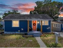 Charming blue single-story home with a welcoming coral-colored front door and sunset sky at 10562 Lake Dr, Seminole, FL 33772