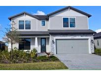 Two-story home with gray siding, stone accents, a two-car garage and professionally landscaped front yard at 17130 Moonflower Dr, Venice, FL 34293