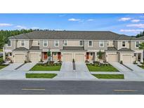 A row of beautiful townhomes with gray roofs and matching garages with landscaping along the driveways at 2204 Paravane Way, Wesley Chapel, FL 33543