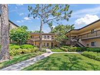 Beautiful condo exterior with well-maintained landscaping, lush green grass, and charming two-story buildings on a sunny day at 2693 Sabal Springs Cir # 201, Clearwater, FL 33761
