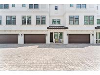 Charming townhome exterior features a brown garage door and light colored brick paver driveway at 310 S Habana Ave # 5, Tampa, FL 33609