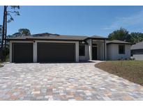 Newly constructed home with a paver driveway leading to a three-car garage at 3125 Tucson Rd, North Port, FL 34286