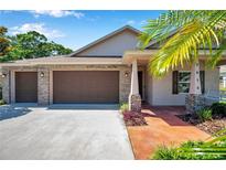 Inviting home with a brick-accented facade, a three-car garage, and a charming front porch at 3610 Montero Ct, Sun City Center, FL 33573