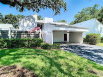 Bright home with white facade, carport, modern privacy fence, tidy landscaping, and an American flag at 4137 Northmeadow Cir, Tampa, FL 33618