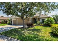 Lovely single-story home with a manicured lawn, mature trees, and a three-car garage at 4410 Natures Reach Ter, Parrish, FL 34219