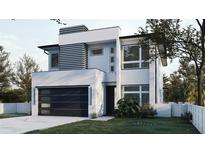 Contemporary home featuring a modern facade, sleek garage door, and manicured lawn at 5406 N Pershing Pl, Tampa, FL 33603