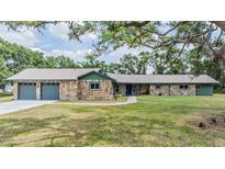 Charming stone home featuring an attached two-car garage and a well-manicured lawn at 6702 Towhe Dr, Seffner, FL 33584