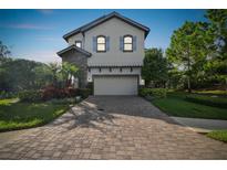 Charming two-story home with a brick driveway and well-manicured landscaping at 1341 Marinella Dr, Palm Harbor, FL 34684