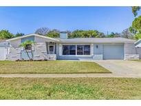 Charming single-story home featuring a well-manicured lawn, and a light blue exterior color scheme at 1560 Simmons Dr, Clearwater, FL 33756