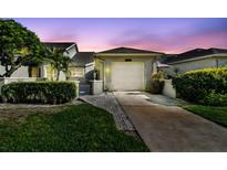 Charming villa features a one-car garage, a private gated courtyard, and lush landscaping with a twilight sky at 232 Hunter Ct, Palm Harbor, FL 34684