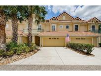 Inviting townhome with a two-car garage, tropical landscaping, and an attractive tile roof at 2674 Tanglewood Trl, Palm Harbor, FL 34685