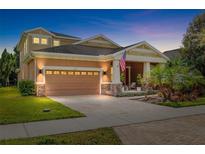 Inviting two-story home with a two car garage, a brick paved driveway and a cozy front porch with decorative landscaping at 5310 Sanderling Ridge Dr, Lithia, FL 33547