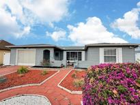 Charming single-story home with attached garage, a red brick walkway and lovely landscaping at 8413 Moulton Dr, Port Richey, FL 34668