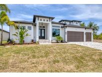 Stunning modern home with a three-car garage, beautiful landscaping, and a striking entrance at 9412 President Cir, Port Charlotte, FL 33981