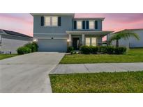 Charming two-story home featuring a manicured lawn, elegant stone accents, and an attached two-car garage at 10749 Tally Fawn Loop, San Antonio, FL 33576