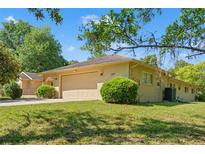 Beige single-story home with a large two-car garage and a lush green lawn at 1379 Matthew Ave, Spring Hill, FL 34609