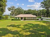 Charming single-story home featuring a well-manicured lawn and verdant shrubbery at 1414 Stephens Oak Ct, Plant City, FL 33567