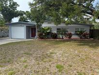 Charming single story home with attached garage, red door, and tropical landscaping at 1542 Sherwood St, Clearwater, FL 33755
