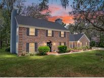 Charming two-story brick home featuring a well-manicured lawn and mature landscaping during a vibrant sunset at 17515 Drake Ct, Lutz, FL 33559
