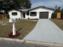 Charming single-story home featuring a freshly painted exterior, modern garage door, and a well-manicured yard at 29813 69Th N St, Clearwater, FL 33761
