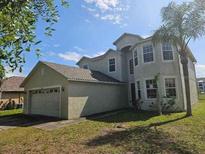 Two-story home with an attached two-car garage, manicured lawn, and palm tree, showcasing curb appeal at 3109 Chessington Dr, Land O Lakes, FL 34638
