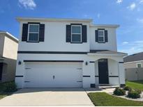 Two-story stucco home with a two car garage, dark shutters, and minimal landscaping at 32699 Dashel Palm Ln, Wesley Chapel, FL 33543