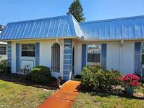 Charming home featuring a blue metal roof, blue shutters, and manicured landscaping at 4206 Tamargo Dr # 4206, New Port Richey, FL 34652