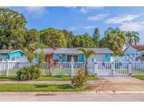 Charming blue single-story home featuring a white picket fence and well-manicured lawn at 6219 57Th N Ave, St Petersburg, FL 33709