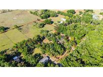 An aerial view shows the property lines and surrounding landscape with lush greenery and mature trees at 27477 Old Trilby Rd, Brooksville, FL 34602
